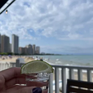 a person holding a glass of water with a lime slice in it