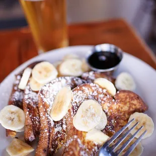 a plate of french toast with bananas and powdered sugar