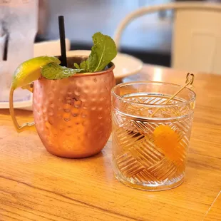 a copper mug and a glass with a drink on a table