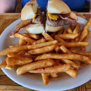 Bacon cheese burger with mustard and pickles and french fries