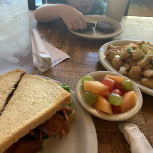 Pastrami BLT on sourdough with a fruit cup and home fries