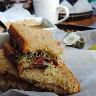 Vegan sandwich with avocado, sprouts, tomato and pecans.