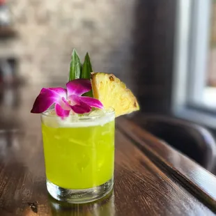 a pineapple drink with a purple flower garnish