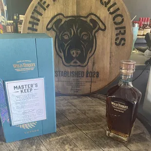 a bottle of white dog whiskey next to a barrel sign