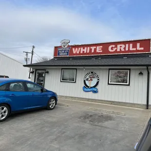 a blue car parked in front of a restaurant