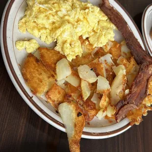 a plate of eggs, bacon, and hash browns