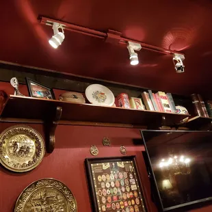 a red wall with a shelf of books and plates