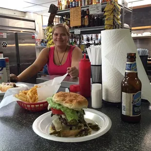 a woman sitting at a counter with a hamburger and fries