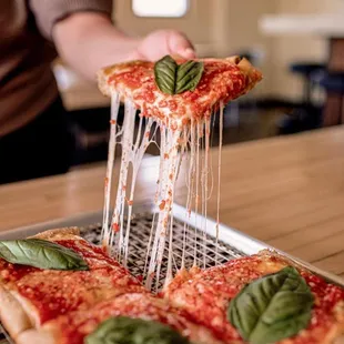 a person holding a slice of pizza