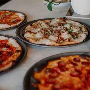 four different pizzas on a table