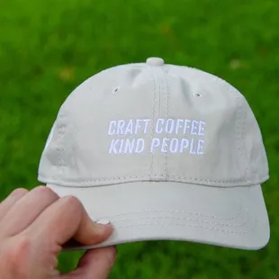 a hand holding a white cap that says craft coffee kind people