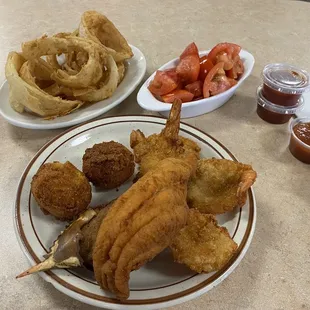 Combo platter with 4 shrimp, 1 catfish, and two hush puppies with tomato salad and a mound of onion rings.
