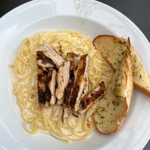 a plate of pasta with chicken and bread
