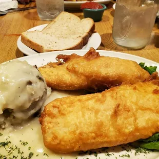 Fish dinner with mashed potatoes and chicken gravy.  Fresh bread.