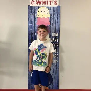 a young boy standing in front of a giant sign
