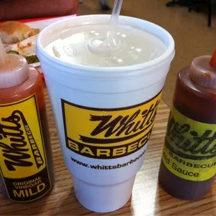 a cup of hot sauce and two bottles of ketchup