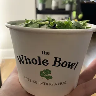 a hand holding a cup of salad