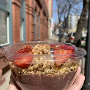 a hand holding a bowl of fruit