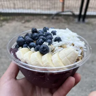 a hand holding a bowl of fruit