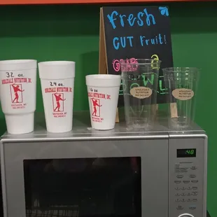 a microwave with cups on top of it