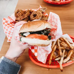 a person holding a sandwich and french fries