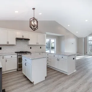 a kitchen with white cabinets and wood floors