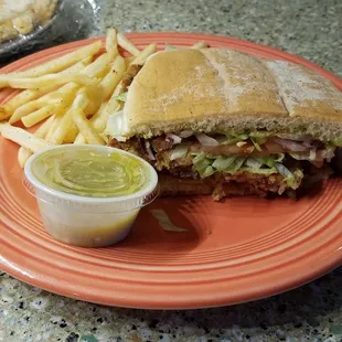 Half of torta filled with yummy fried pork, salad toppings,  and quacamole.