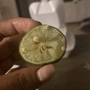 a person holding a lime in their hand