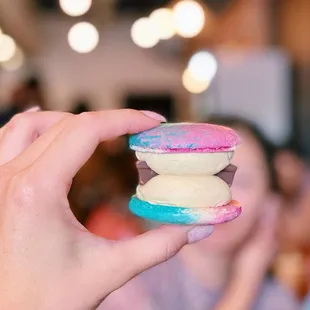 a hand holding a colorful macaron