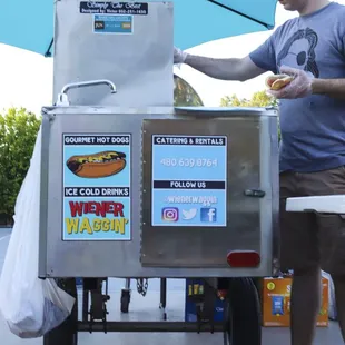 a man standing next to a hot dog cart