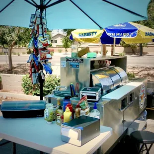 a hot dog stand with a blue umbrella