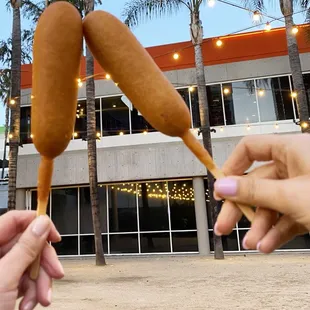 a person holding a hot dog on a stick