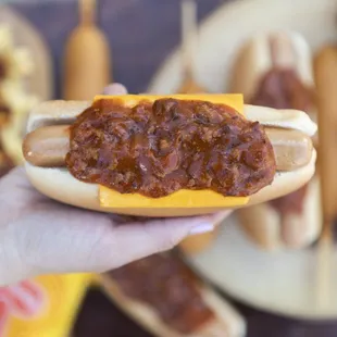 a hand holding a chili dog