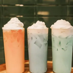 three different drinks on a wooden tray