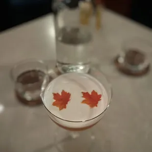 a glass filled with liquid and a maple leaf