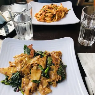 a plate of stir fried noodles and a glass of water