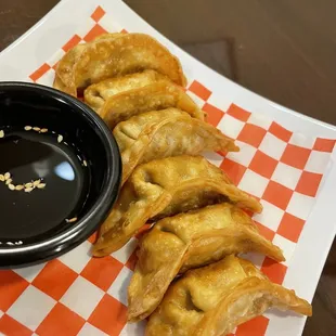 a plate of dumplings and a bowl of dipping sauce