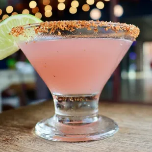 a pink cocktail with a lime slice on the rim