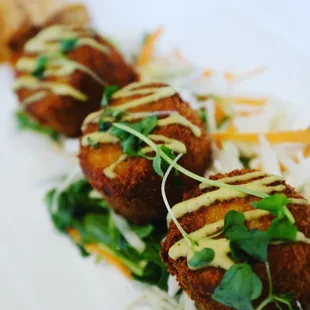 three fried fish cakes on a white plate