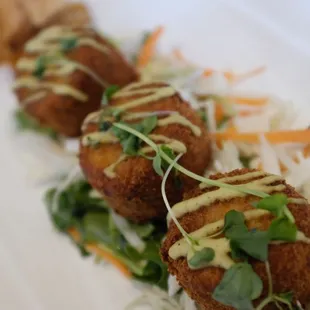 three fried meatballs on a bed of coleslaw