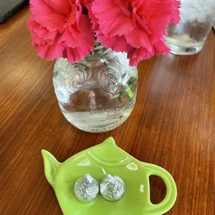 a green teapot and pink flowers