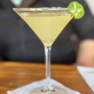 a martini with a lime garnish on the rim