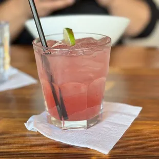 a glass of watermelon drink with a straw and a lime garnish