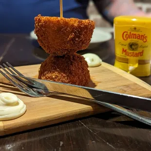 a teddy bear on a wooden cutting board with a fork and knife