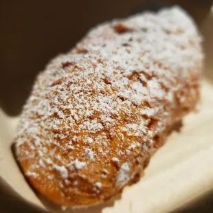 a powdered sugared pastry in a paper container