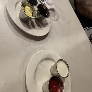 two plates of condiments on a table