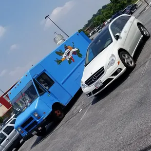 a blue food truck and a white car