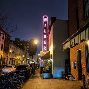 the neon sign for wilder&apos;s on a city street