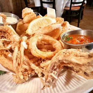 a plate of fried onion rings and dipping sauces