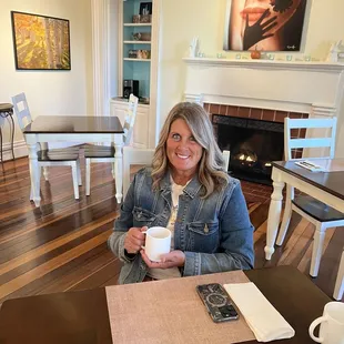 Enjoying a cup of coffee in front of the fireplace.